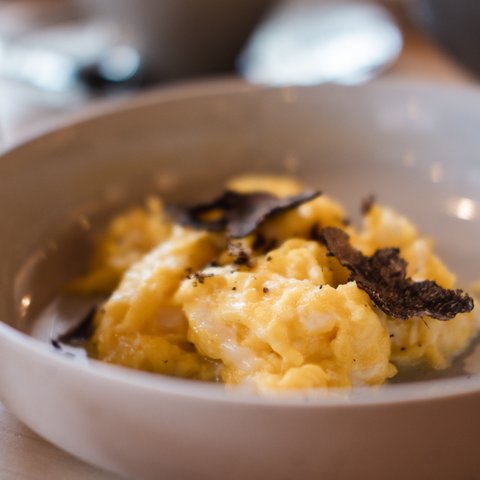 Brunch - das Langschläferfrühstück Rührei mit schwarzen Trüffelscheiben in einer weißen Schüssel