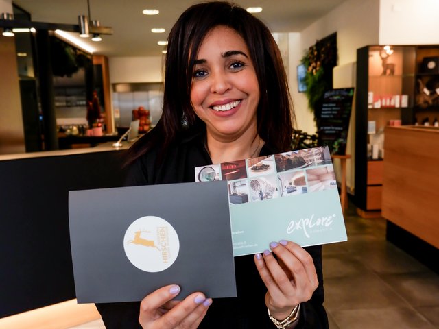 Home Frau lächelt und hält Prospekte in einem modernen Empfangsbereich