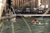 Person schwimmt in einem Pool vor einer Terrasse mit Liegestühlen