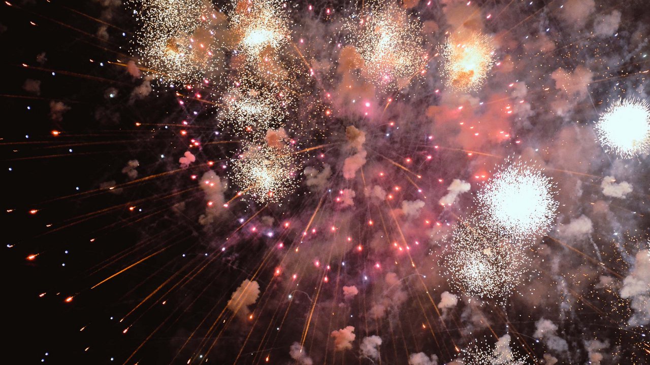 Colorful fireworks light up the night sky with smoke