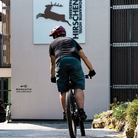Looking for a hotel with bike rental in Bavaria? Cyclist riding in front of Romantik Hotel Hirschen Parsberg