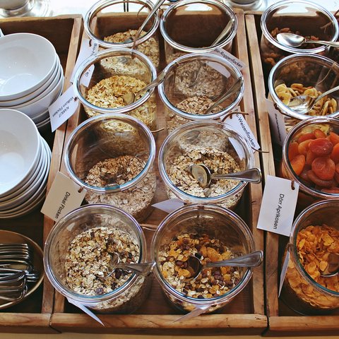 Romantik Hotel Hirschen: Frühstück Verschiedene Müslis und getrocknete Früchte in Gläsern mit Schälchen und Löffeln