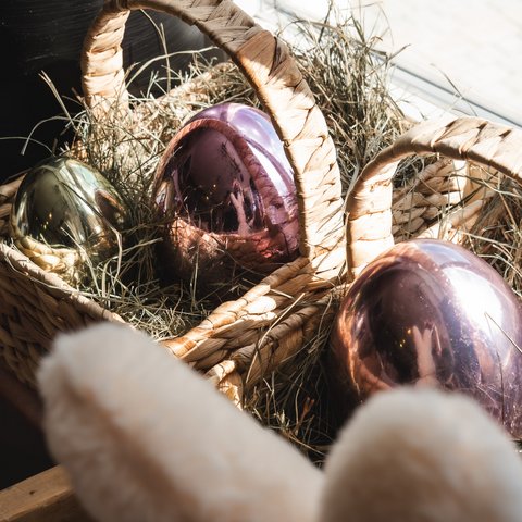 Nachhaltiges Hotel in Bayern mit Hirschenmanufaktur Weidenkorb mit dekorativen glänzenden Ostereiern im Stroh