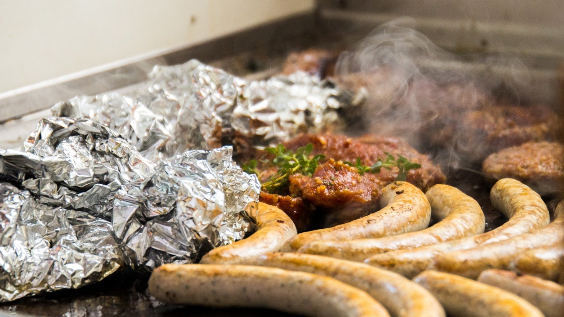 Tagungshotel mit Events gesucht? Bratwürste, Alufolie und Fleisch auf einem heißen Grill mit Dampf