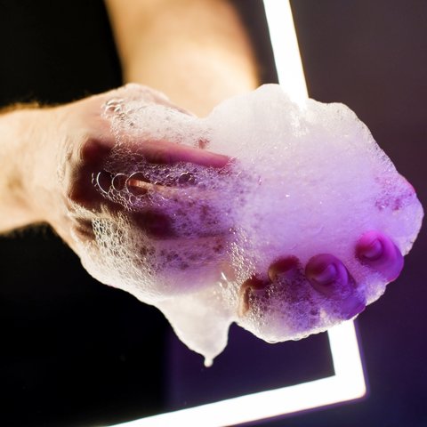 Tageswellness in der Oberpfalz Hand mit Schaum vor dunklem Hintergrund und neonlicht