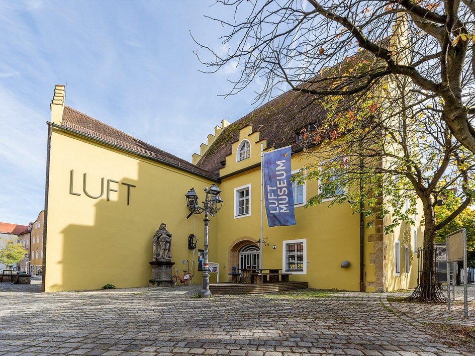 Wandern in der Oberpfalz: Aktiv in der Natur Gelbes Gebäude mit LUFT Museum Fahne und Statue im Hof
