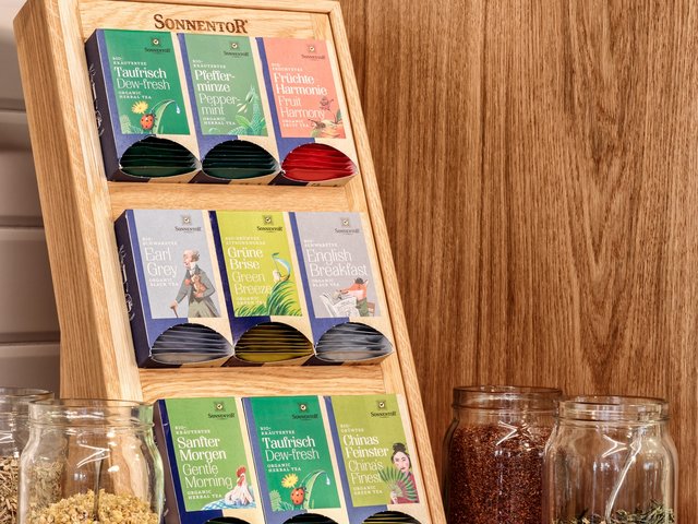 Romantik Hotel Hirschen: Bildergalerie Teesorten von Sonnentor in Holzdose auf Küchenarbeitsplatte mit Gläsern