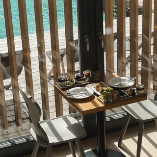 Home Kleiner Tisch mit Essen und zwei Stühlen neben Fenster mit Poolblick