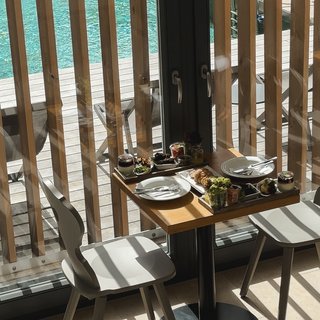 Looking for somewhere for conferences in Bavaria? Small table with food and two chairs by window overlooking swimming pool