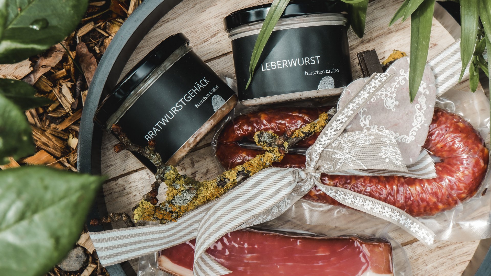 Nachhaltiges Hotel in Bayern mit Hirschenmanufaktur Verschiedene Wurst- und Fleischprodukte in Gläsern und Verpackungen auf Holztablett