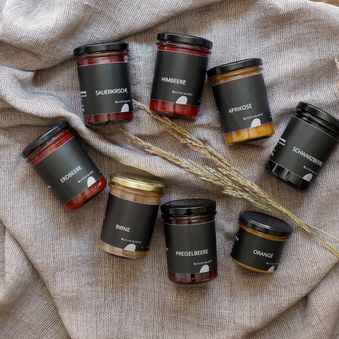 Eco-friendly hotel in Germany with Hirschenmanufaktur Various jam jars with black labels on gray blanket