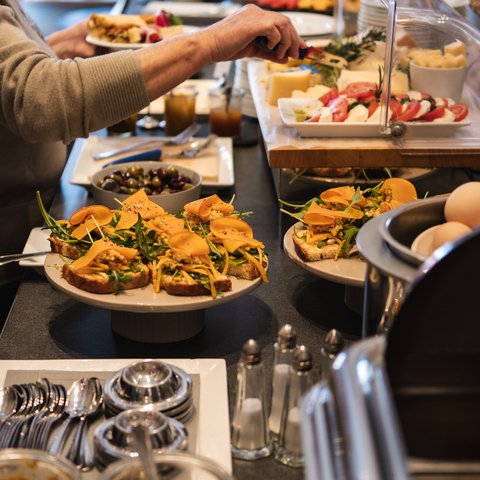 Brunch - das Langschläferfrühstück Person nimmt Essen an einem Buffet mit belegten Broten und frischen Zutaten