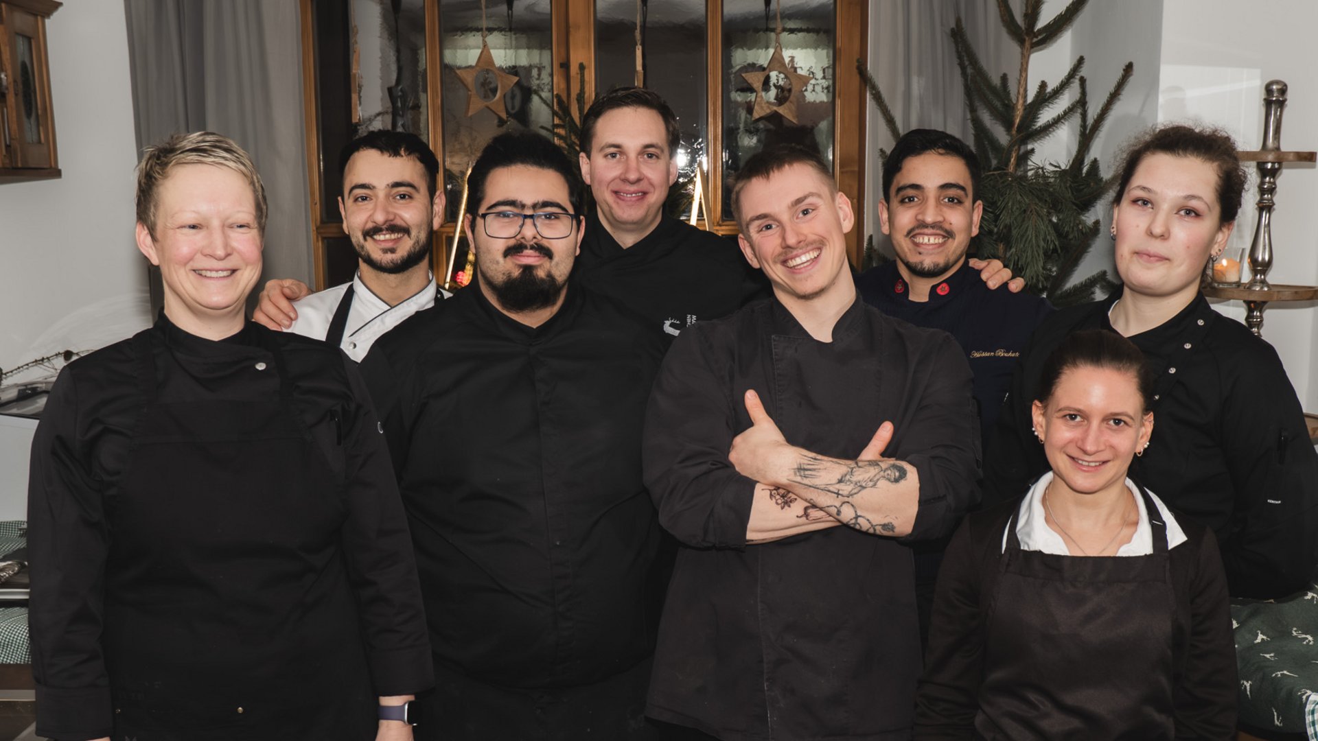 Gasthof Parsberg: Ein Gruß an den guten Geschmack Gruppenfoto von acht lächelnden Küchenmitarbeitern in schwarzer Arbeitskleidung