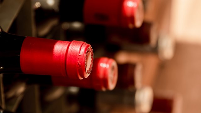 Romantik Hotel Hirschen: Blog Weinflaschen mit roten Kapseln in einem Regal liegend