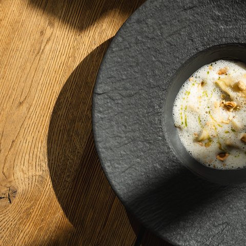 Fine Dining & Gourmet Cuisine in the Upper Palatinate Creamy soup with herb oil and crunchy pieces in a black bowl