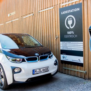 Leistungen und Preise für Tagungen und Konferenzen Elektroauto an Ladestation vor Holzgebäude geparkt