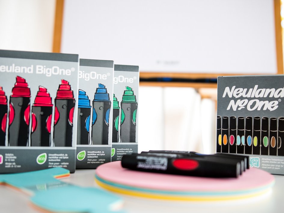 Tagung mit Mehrwert Neuland BigOne Markerpackungen in Rot, Blau und Grün mit farbigen Markern und Notizzetteln