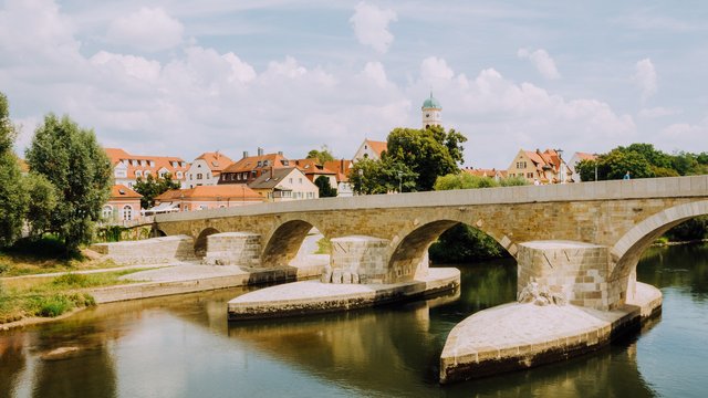 Hotel Oberpfalz: Urlaubsluft schnuppern! Steinbrücke über ruhigen Fluss in einer deutschen Stadt bei sonnigem Wetter
