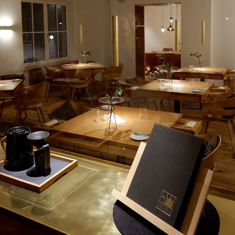 Restaurant in Parsberg: Gourmet genießen Modernes Restaurant mit Holzmöbeln und gedeckten Tischen bei gedämpftem Licht