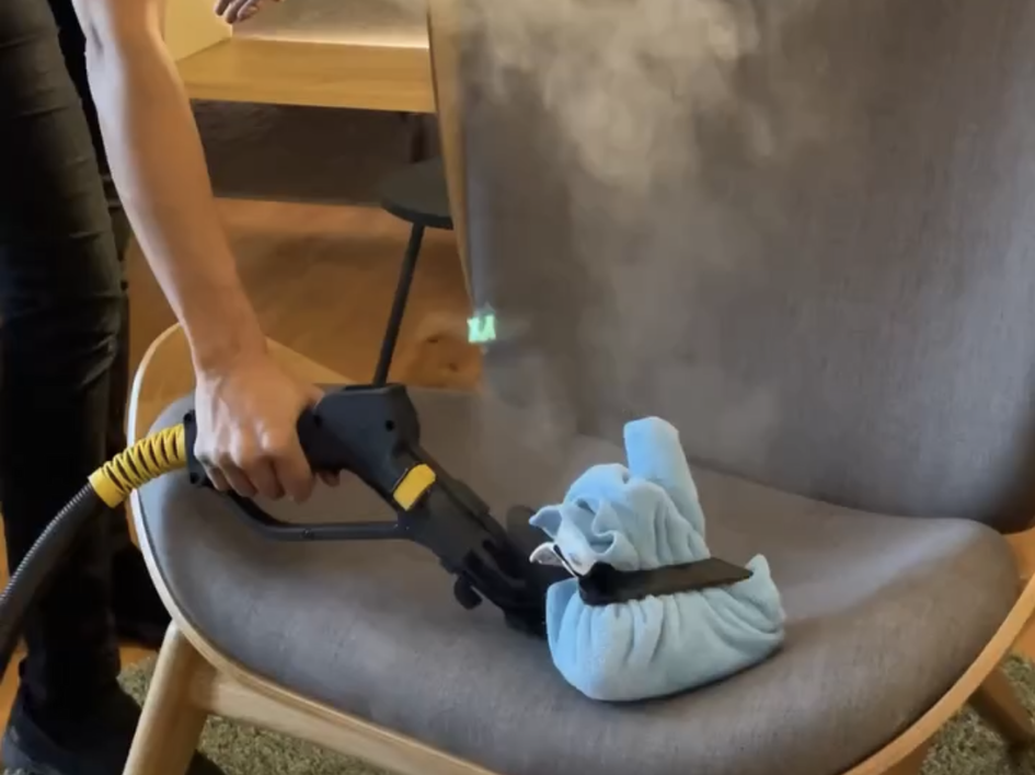 Nachhaltige Hotels in Deutschland gesucht? Person reinigt Stuhl mit Dampfreiniger und blauer Abdeckung