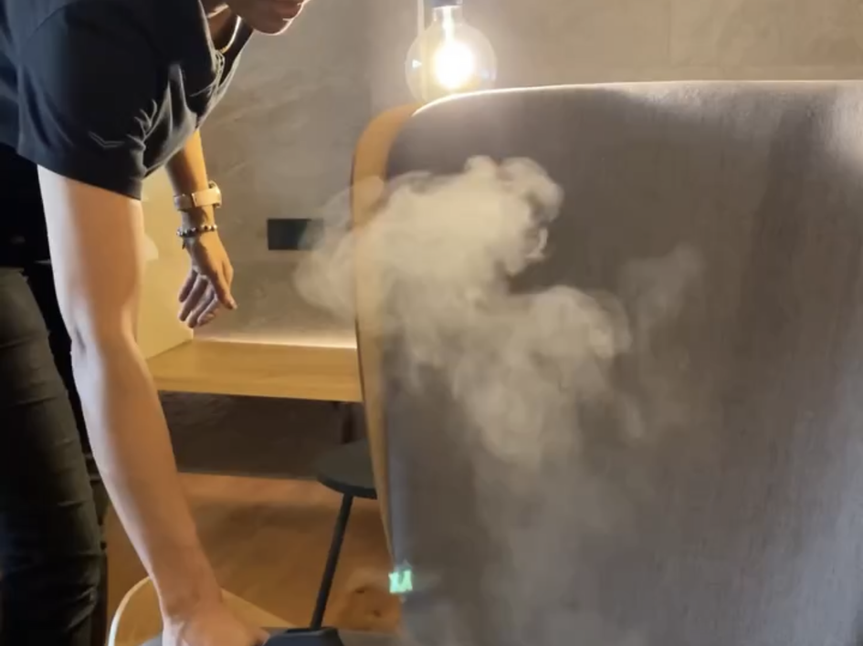 Looking for sustainable hotels in Germany? Person cleaning chair with steam cleaner and blue cover