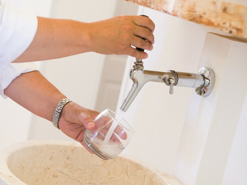 Nachhaltige Hotels in Deutschland gesucht? Person füllt Glas mit Wasser aus einem Wandhahn