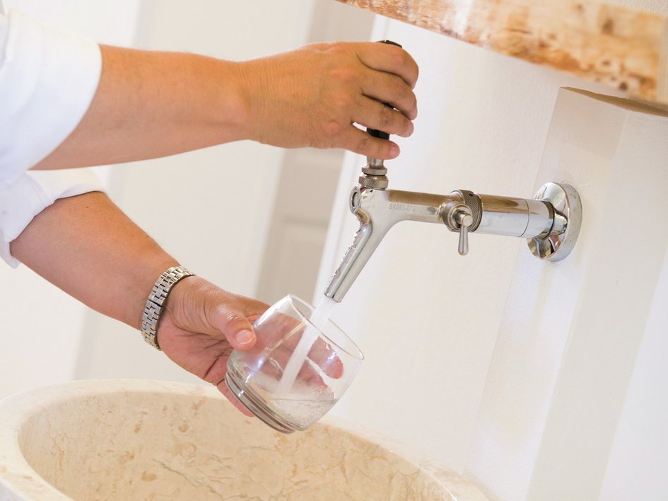 Nachhaltige Hotels in Deutschland gesucht? Person füllt Glas mit Wasser aus einem Wandhahn