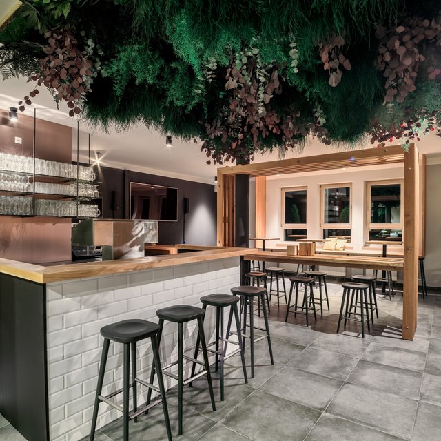 Inclusive services: Everything a stag could want. Modern bar area with stools and hanging green plant installation