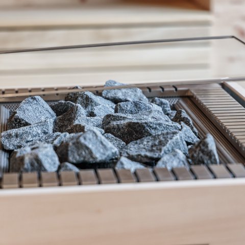 Tageswellness in der Oberpfalz Saunaofen mit heißen Sauna-Steinen in einer Holzsauna