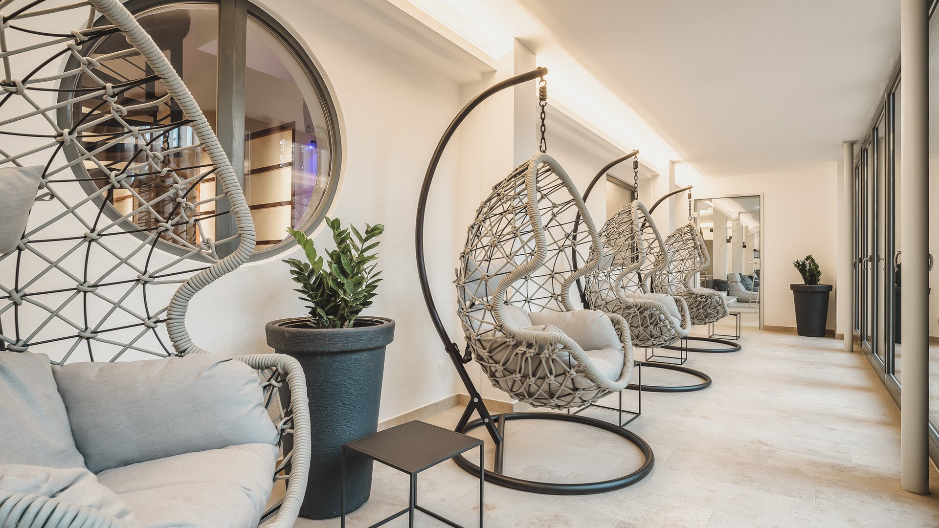 Hotel Oberpfalz: Urlaubsluft schnuppern! Moderner Innenraum mit mehreren hängenden Korbsesseln und Pflanzen