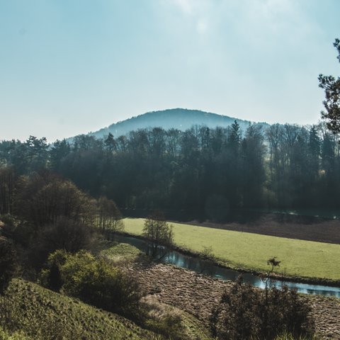 Romantik Hotel Hirschen: Gastgeber & Werte Blick auf einen Fluss, Wiesen und bewaldete Hügel an einem klaren Tag
