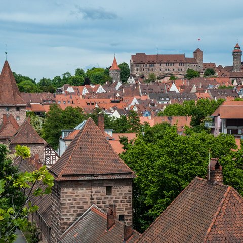 Hotels in Regensburg und Umgebung: kultur-trächtig! Blick auf Nürnbergs Altstadt mit Burg und roten Ziegeldächern unter bewölktem Himmel